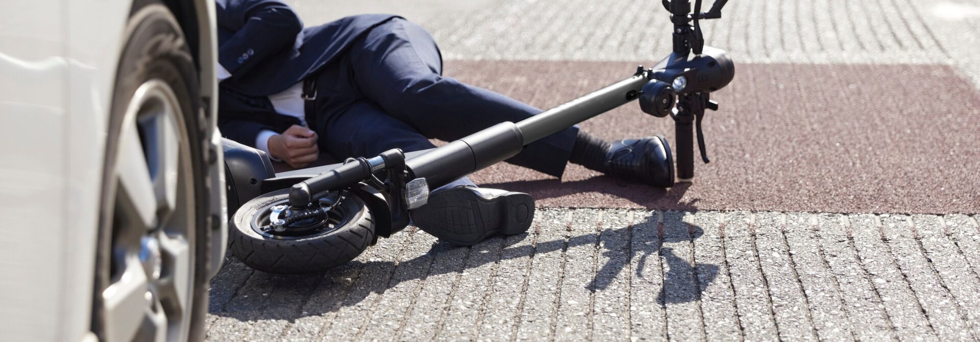 Lower half of man in suit lying on floor after e scooter accident