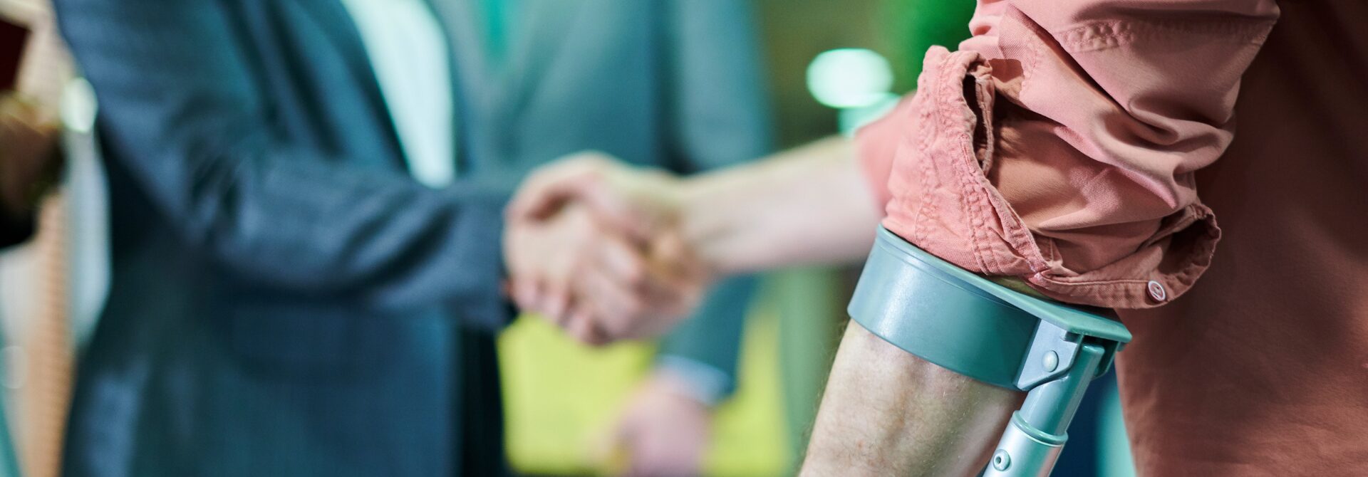 Man on crutches shaking hands with another man, no faces shown