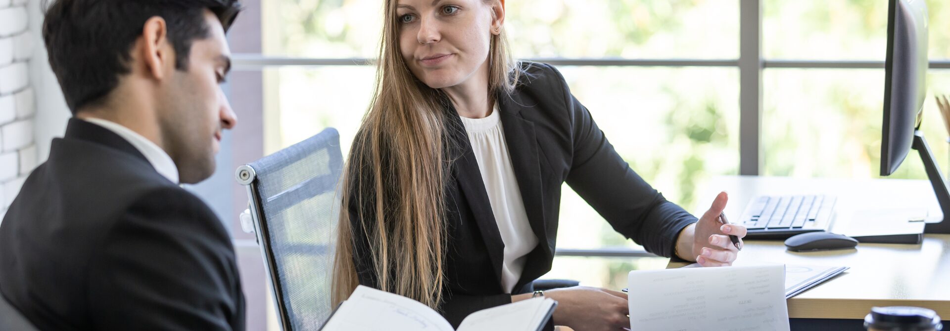 two professional people in a meeting at a desk