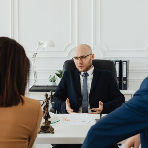 male solicitor behind a desk talking to two clients