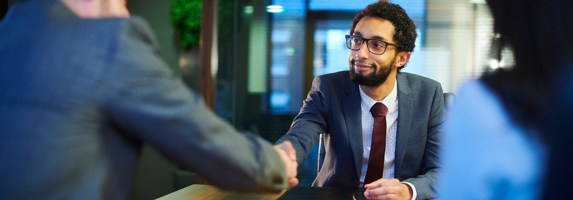 Two men shaking hands across a table