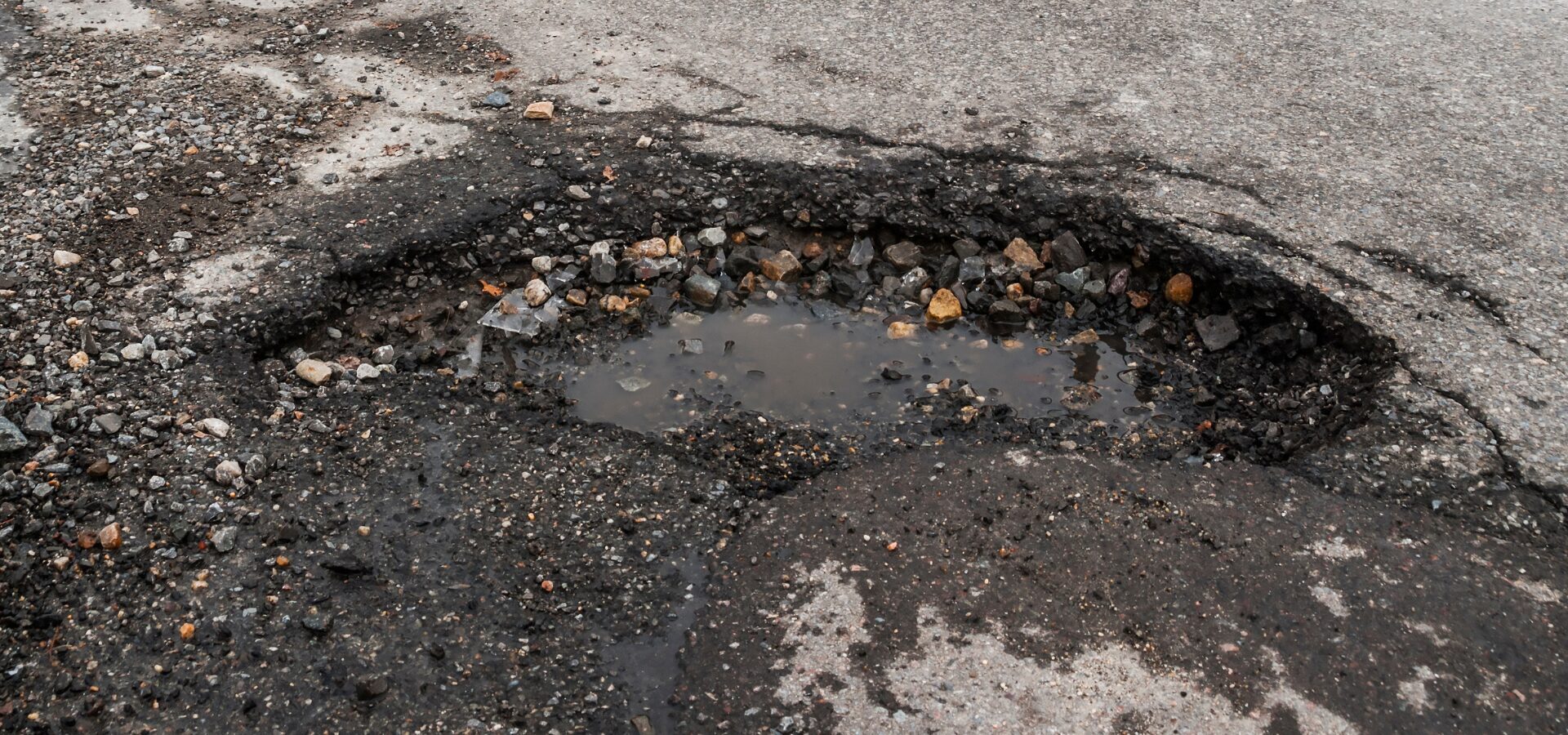 Pothole with water and gravel in